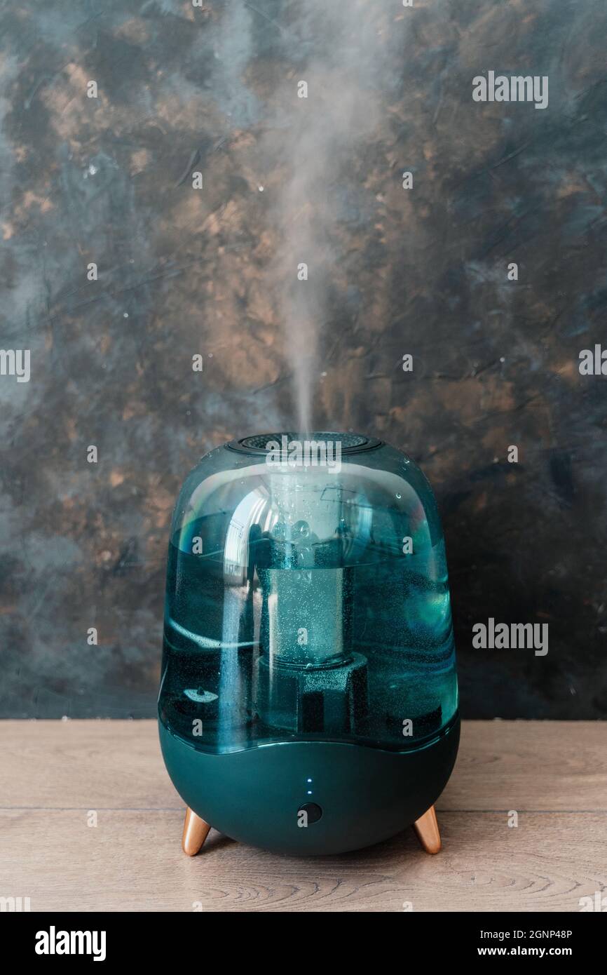 Modern air humidifier on a dark background. Humidifier spreading steam. Stock Photo