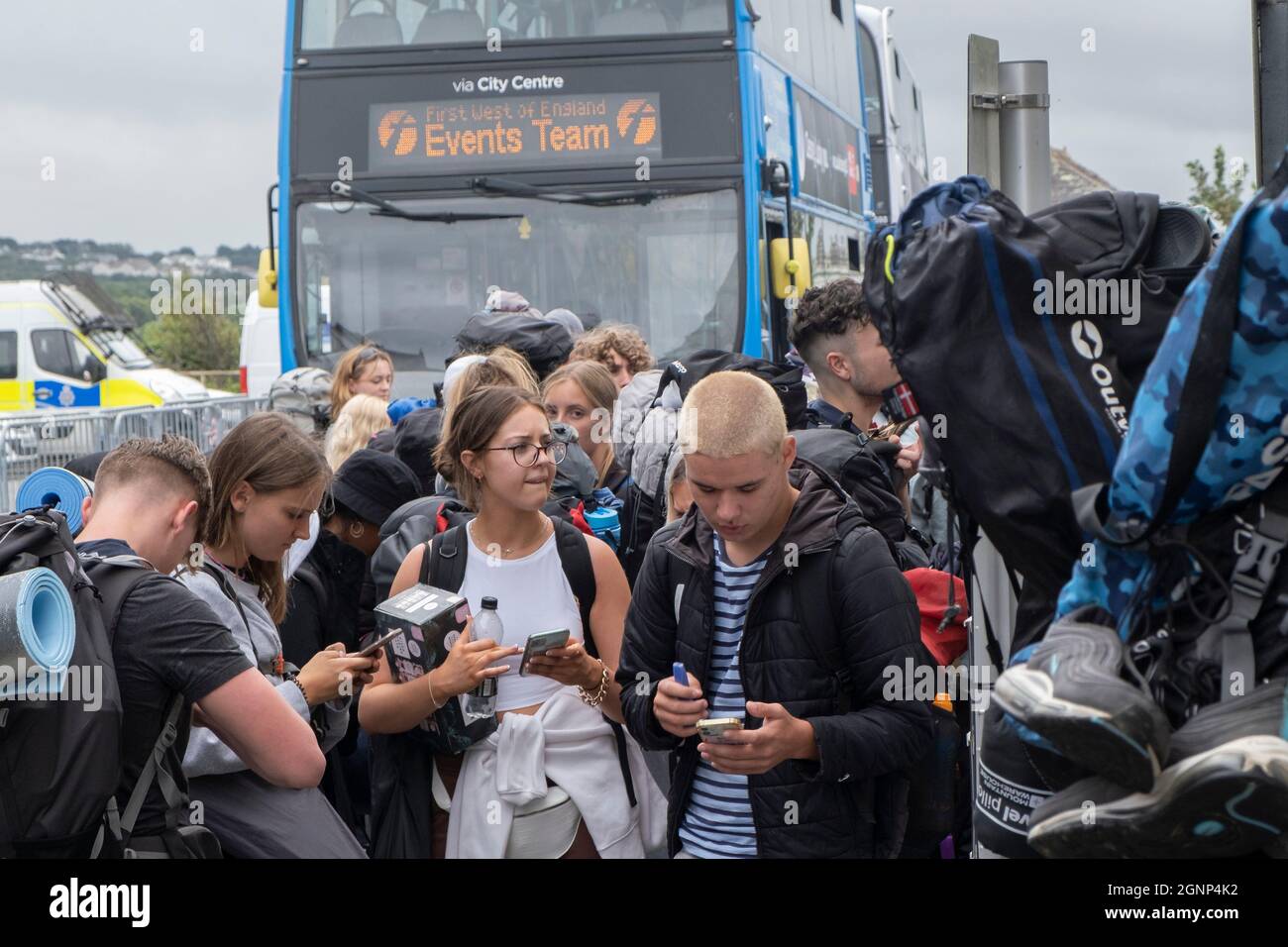 Young people using their mobile phones and queueing for buses to take them to the opening day of The Boardmasters Festival in Cornwall. Stock Photo