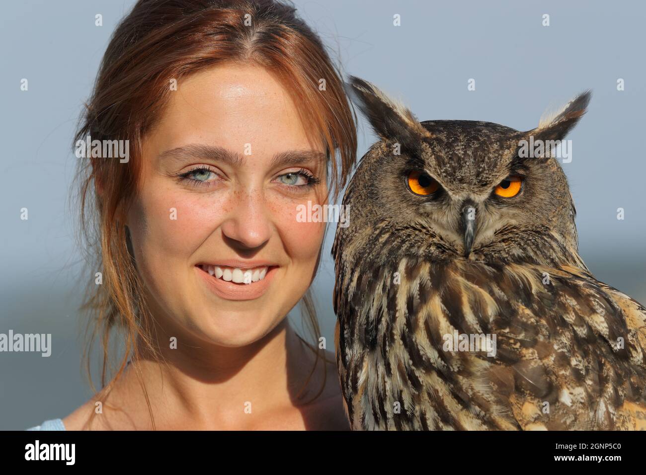Portrait of a happy woman holding royal owl looking at camera Stock Photo