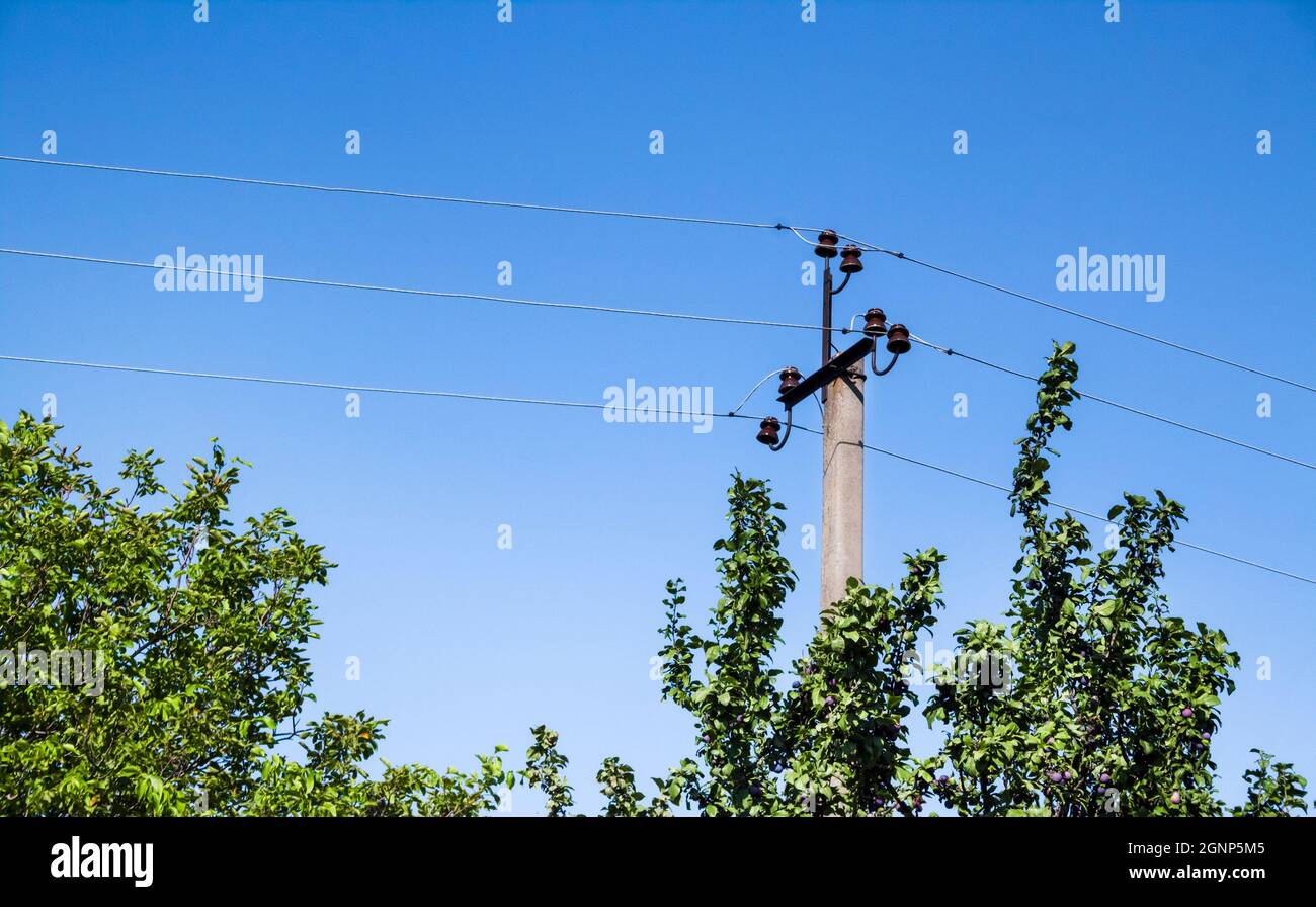 Electric support pole with ceramic elements against blue sky background Stock Photo