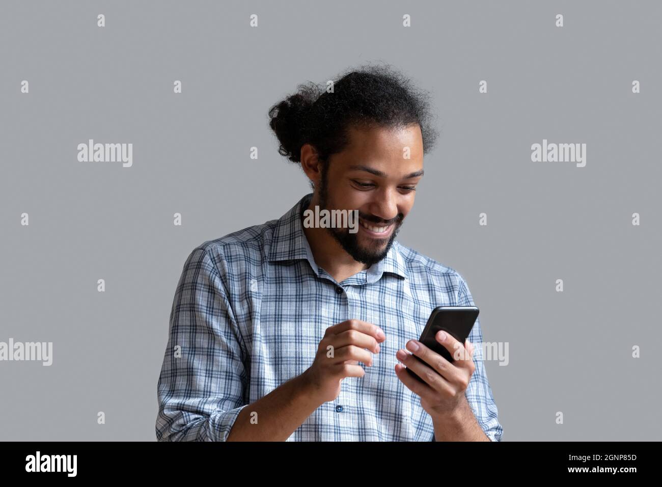 Excited African American man using smartphone on grey background Stock Photo