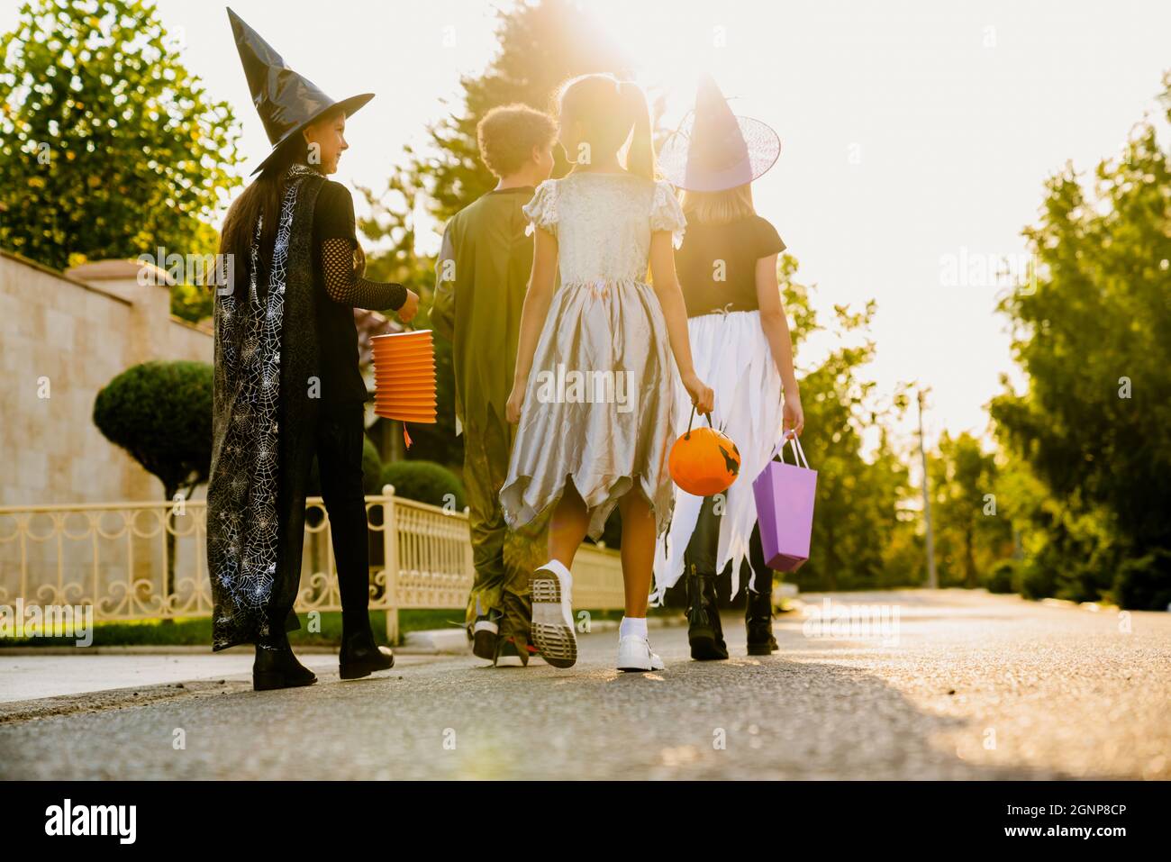 White children in Halloween costumes walking down street during trick ...