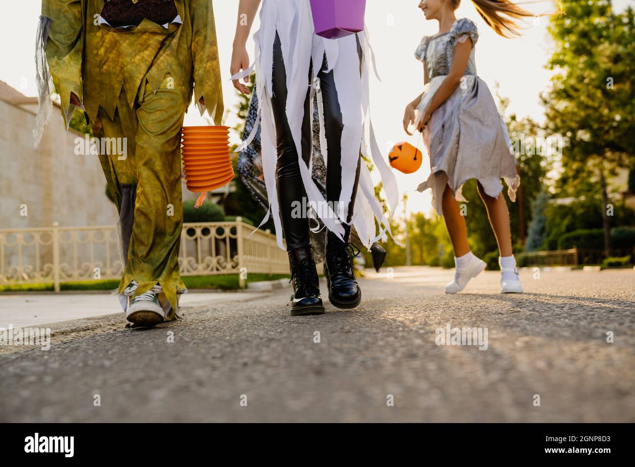 White children in Halloween costumes walking down street during trick ...