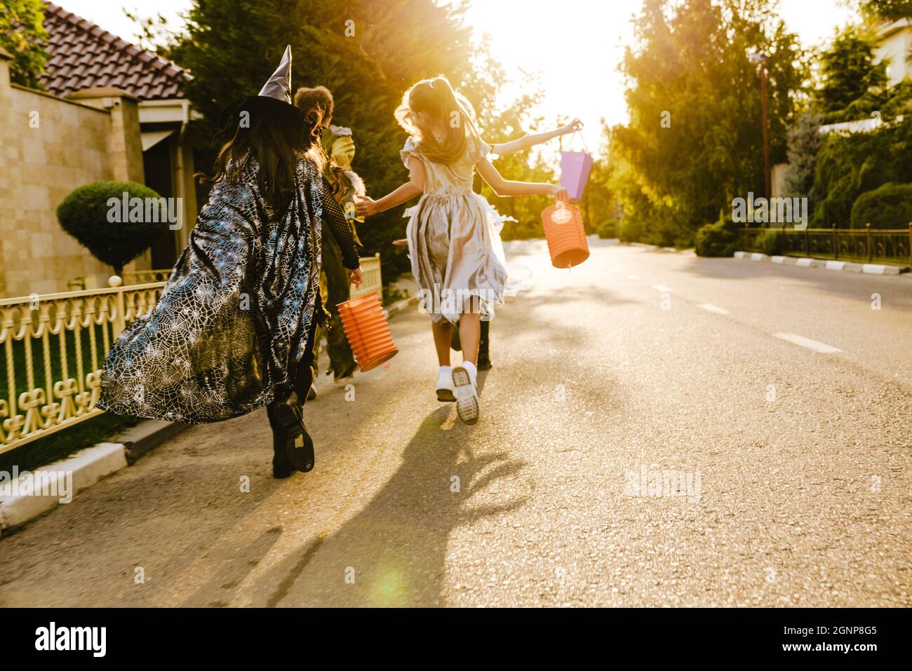 White children in Halloween costumes walking down street during trick ...