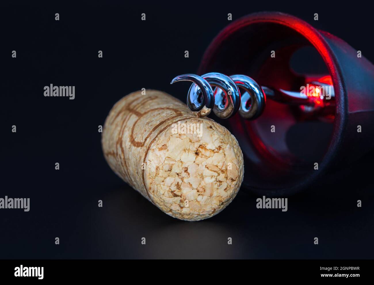 Corkscrew and wine stopper on a dark background with red reflexes. Stock Photo