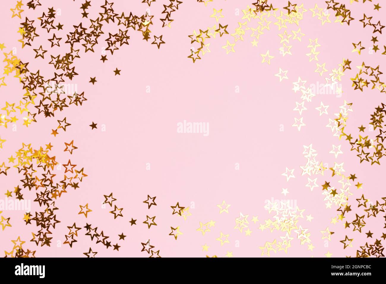 Border frame made of gold colored stars confetti on a pink pastel