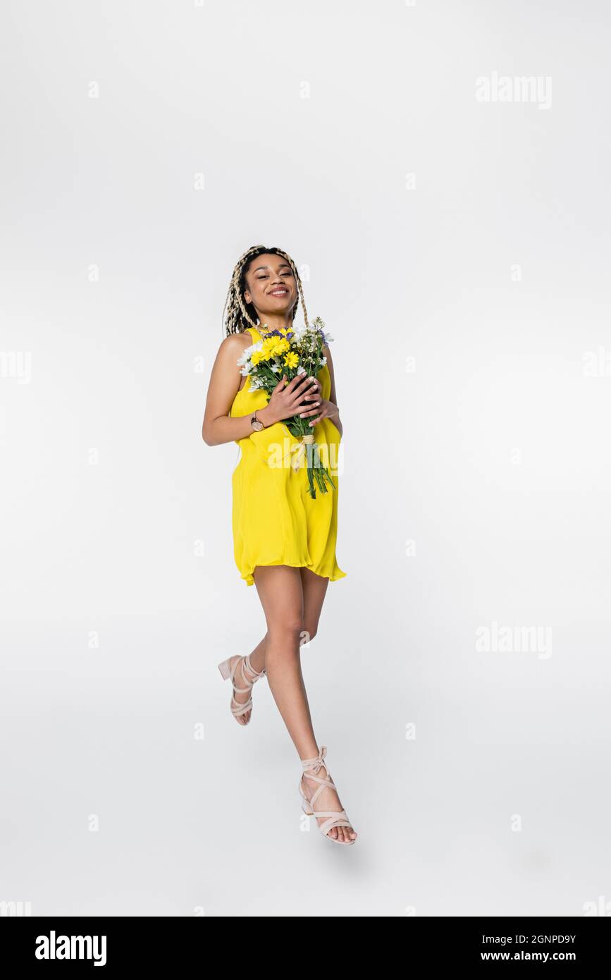 joyful african american woman in bright yellow dress walking in air ...