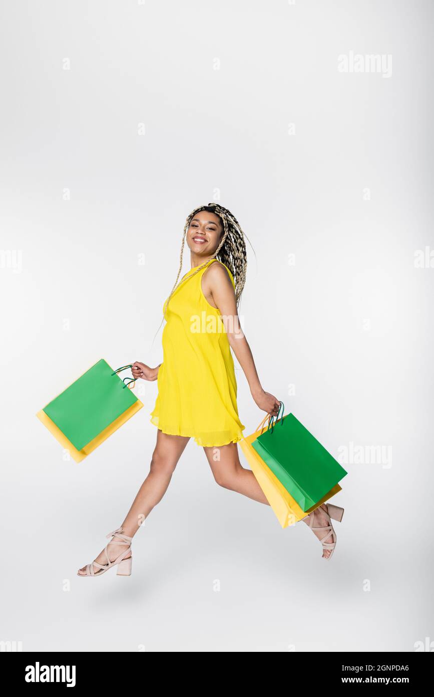 cheerful african american woman smiling at camera while levitating with shopping bags on white Stock Photo