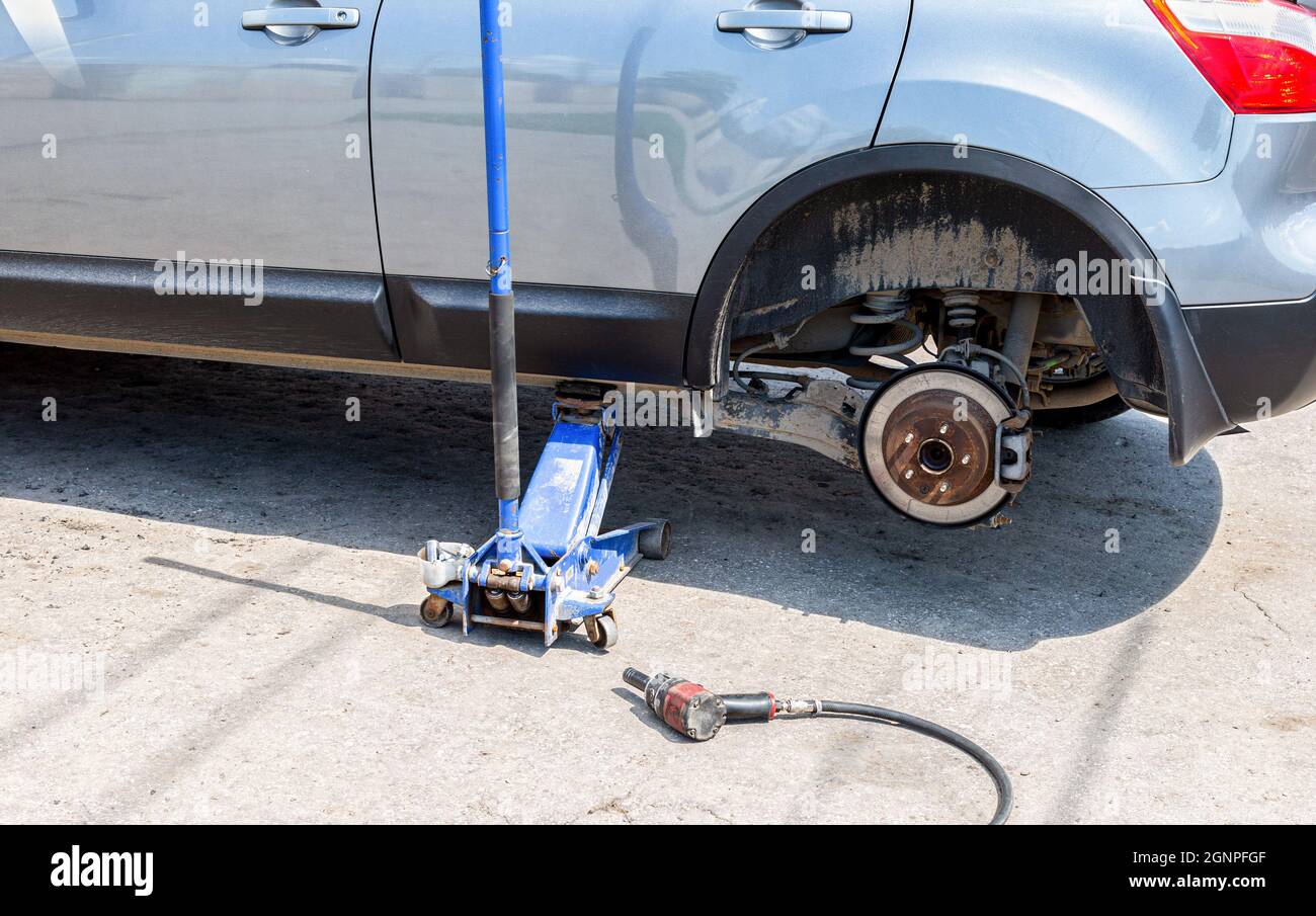 Car at the tire mounting with removed wheel on pneumatic jack. Seasonal