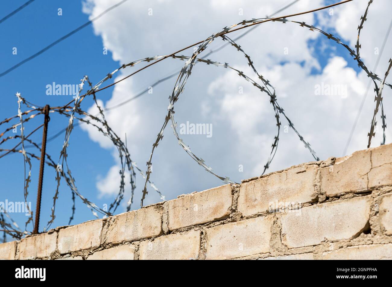 Barbed wire on the fence against a blue sky background. Prison wall