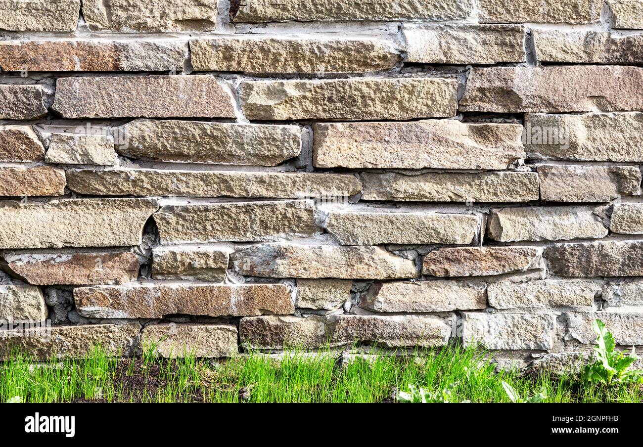 Rough stone wall as creative background texture. Natural stones masonry with uneven seams. Stone wall background Stock Photo