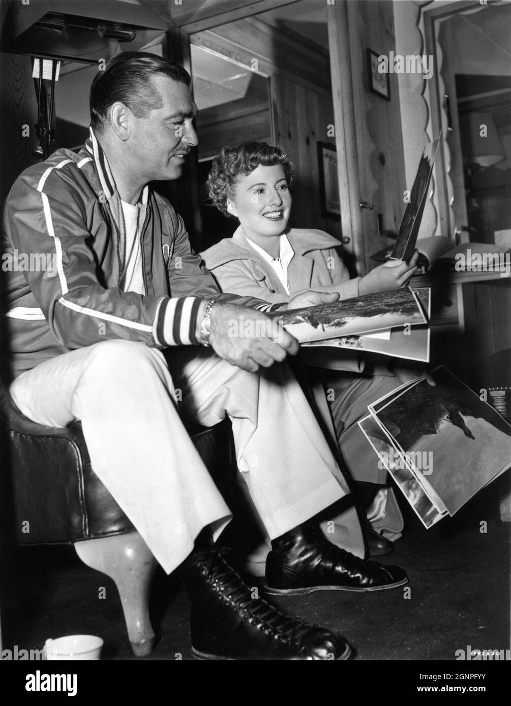 CLARK GABLE and BARBARA STANWYCK on set candid looking at publicity still photos from her previous film The Furies (director Anthony Mann) on set candid during filming of TO PLEASE A LADY 1950 director CLARENCE BROWN story / screenplay Barré Lyndon and Marge Decker costume design Helen Rose Metro Goldwyn Mayer Stock Photo