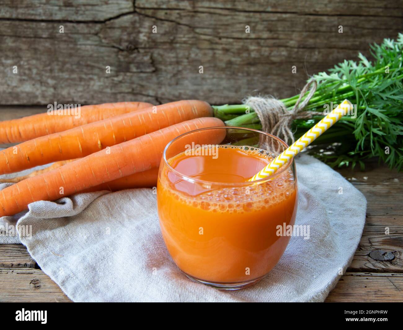 Fresh squeezed carrot juice in a glass on a wooden surface, rustic style  Healthy eating, detox, dieting and vegetarian concept. Stock Photo