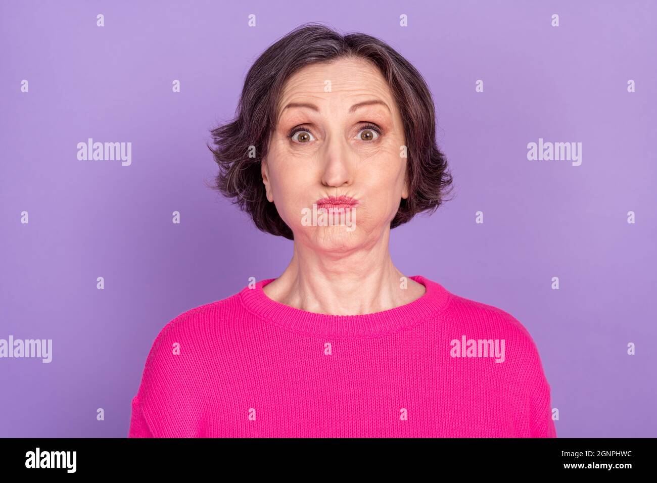 Portrait of attractive funny mature woman holding air in cheeks fooling ...