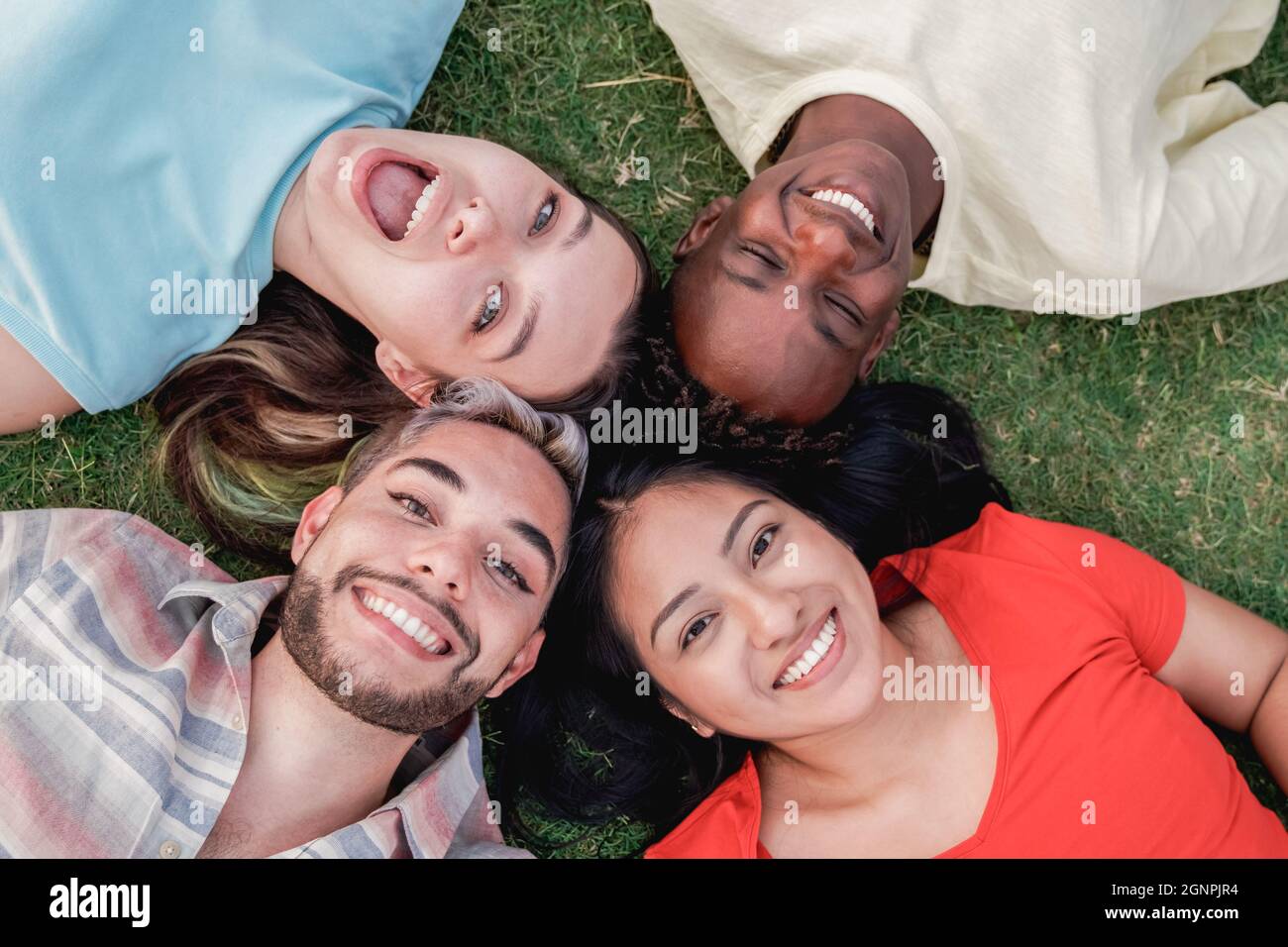 Diverse friends having fun relaxing on the grass outdoor at park city - Focus on gay man face Stock Photo