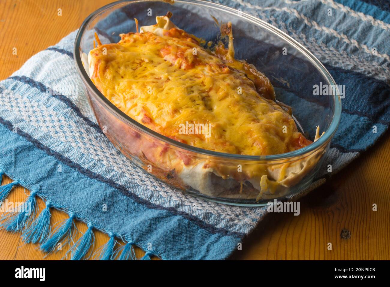 Close up of dinner in casserole dish with Chicken enchiladas garnished with enchilada sauce and cheese Stock Photo