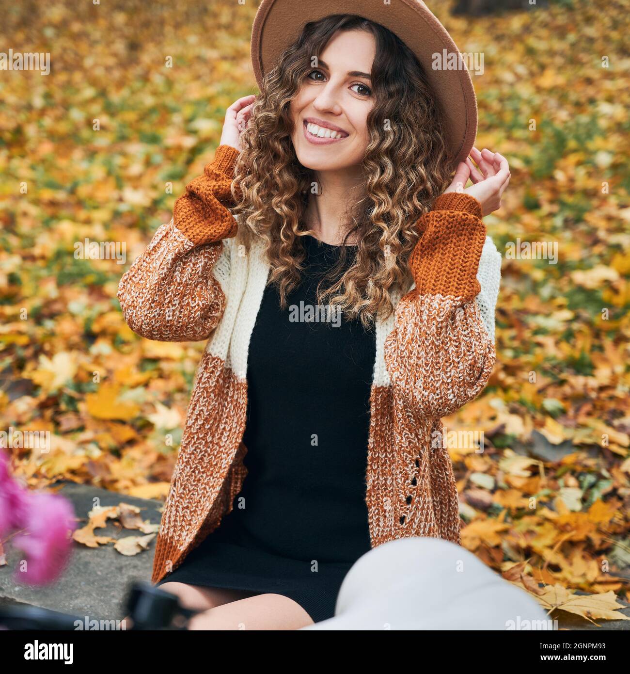 Portrait of beautiful young woman with curly hair posing on the street ...