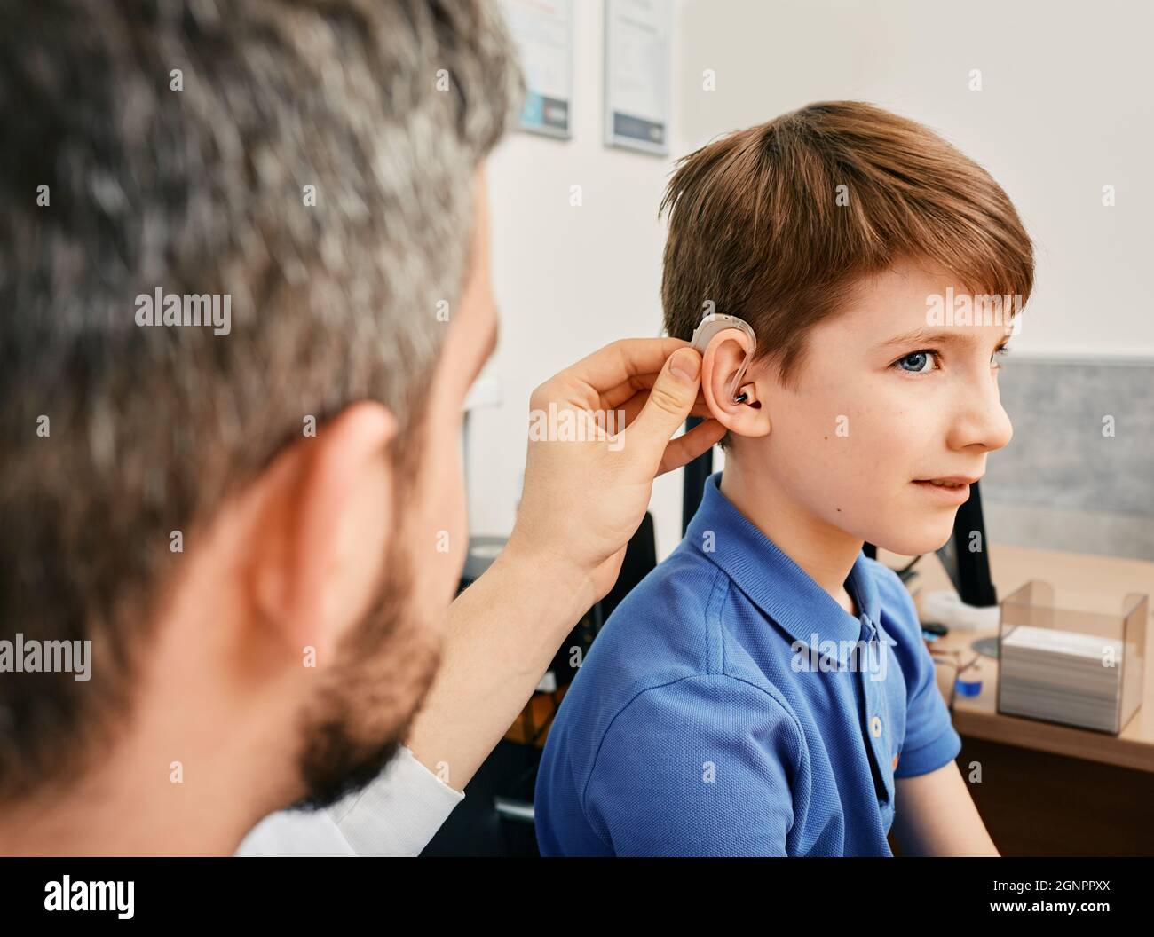 Hearing treatment for a child. Caucasian boy during installation hearing aid by audiologist in hearing clinic Stock Photo