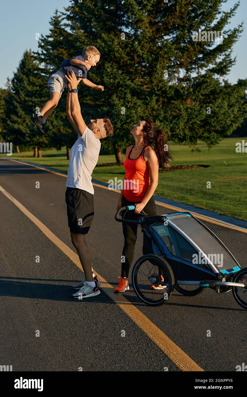 Family having fun outdoors. Father throws up son during leisure with