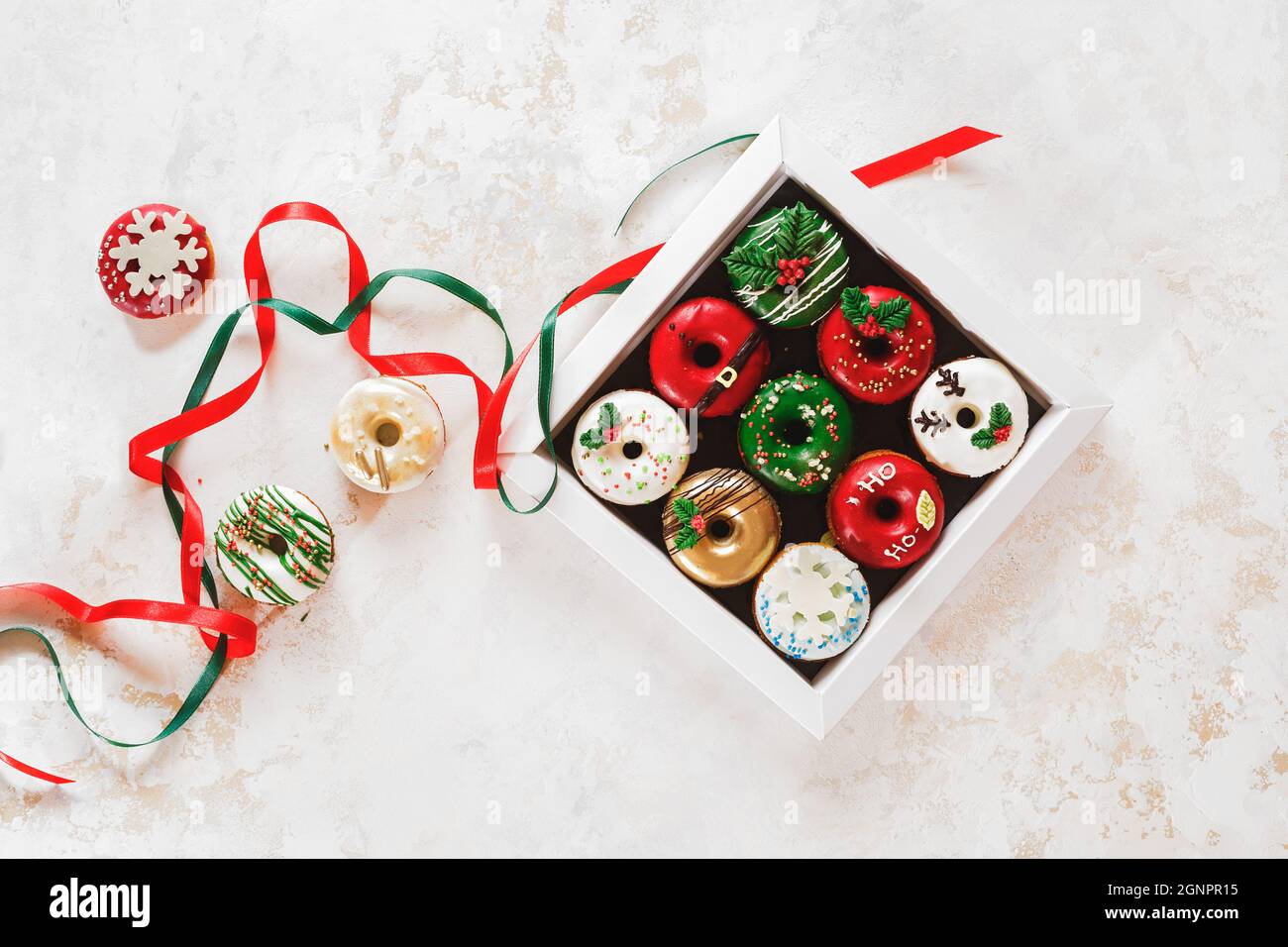 Colorful doughnuts in a gift box and beside. Christmas  Doughnuts with sugar icing  as a gift. Top view, blank space Stock Photo