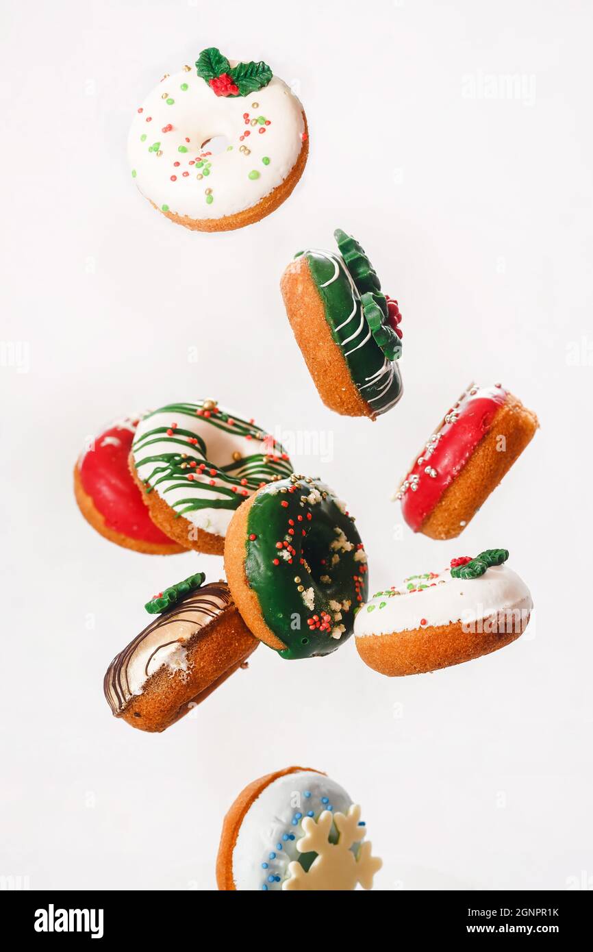 Flying Christmas donuts. Colorful doughnuts with sprinkles falling or flying in motion against white background.  Selective focus Stock Photo