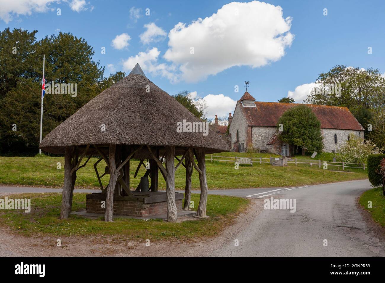 Thatched well on the village green and St. Peter's church beyond, East