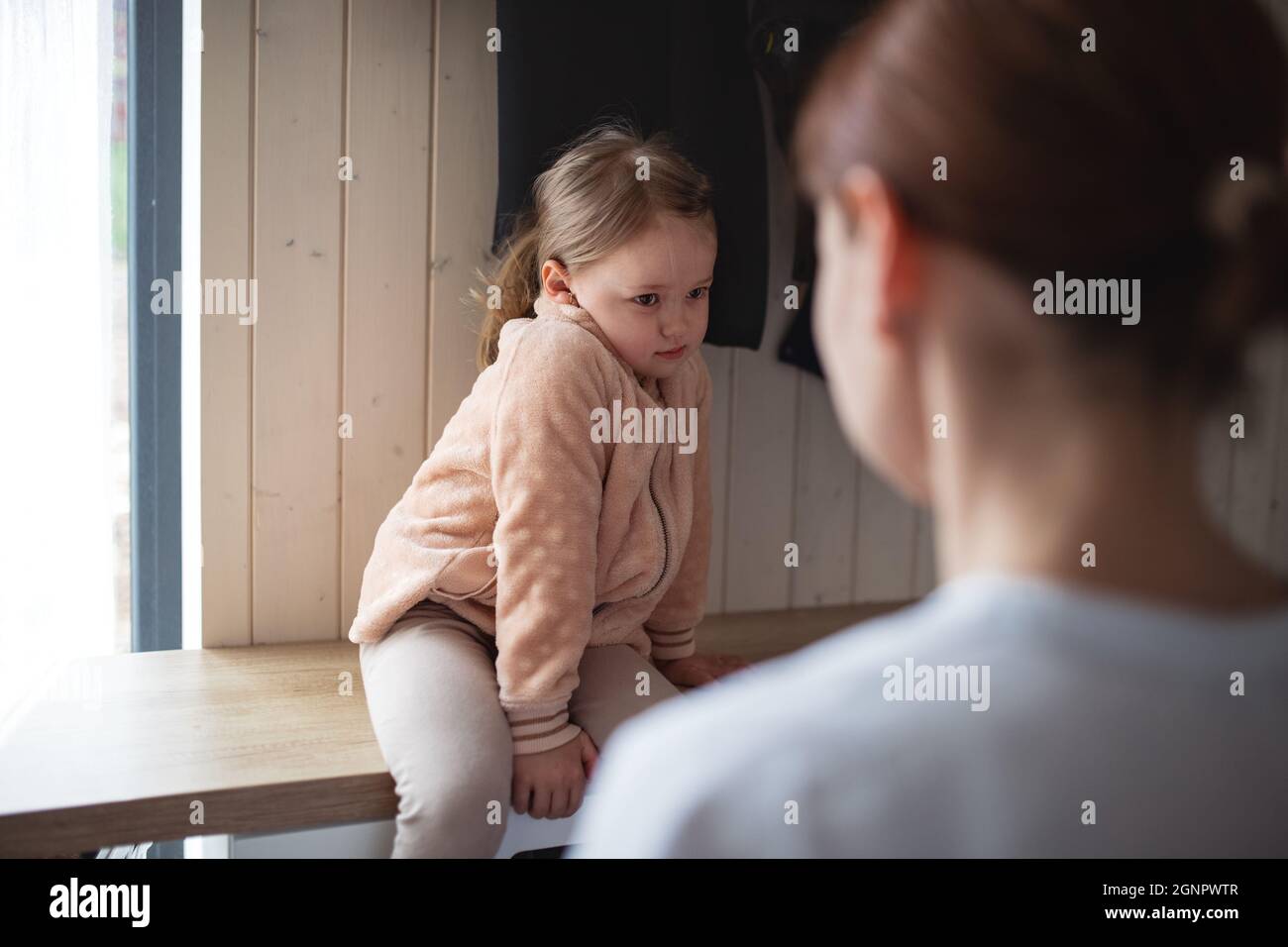 Mother with small daughter in entrance hall indoors in the morning, leaving for work and nursery school. Stock Photo