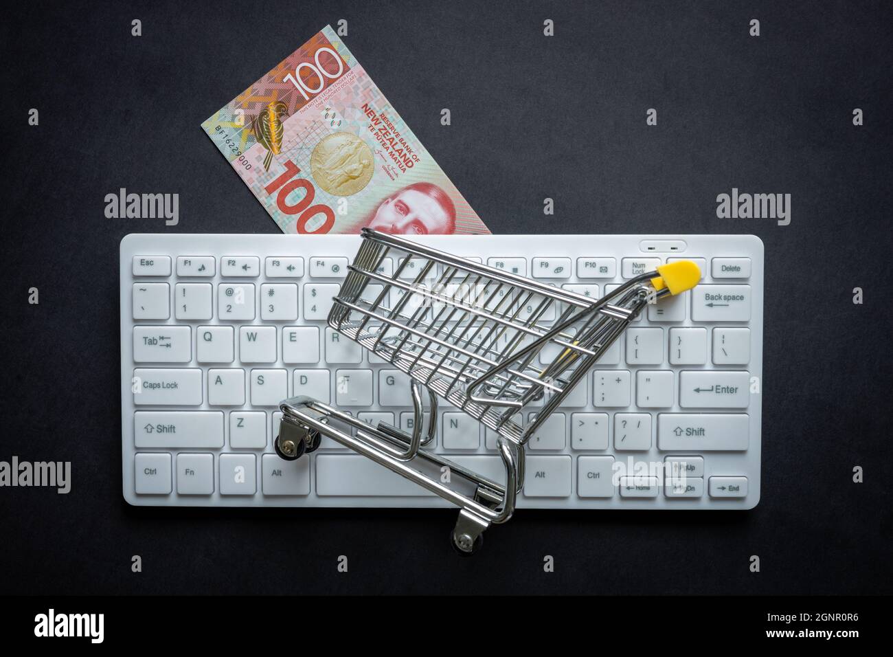 New Zealand dollar, White computer keyboard, Miniature shopping cart ...
