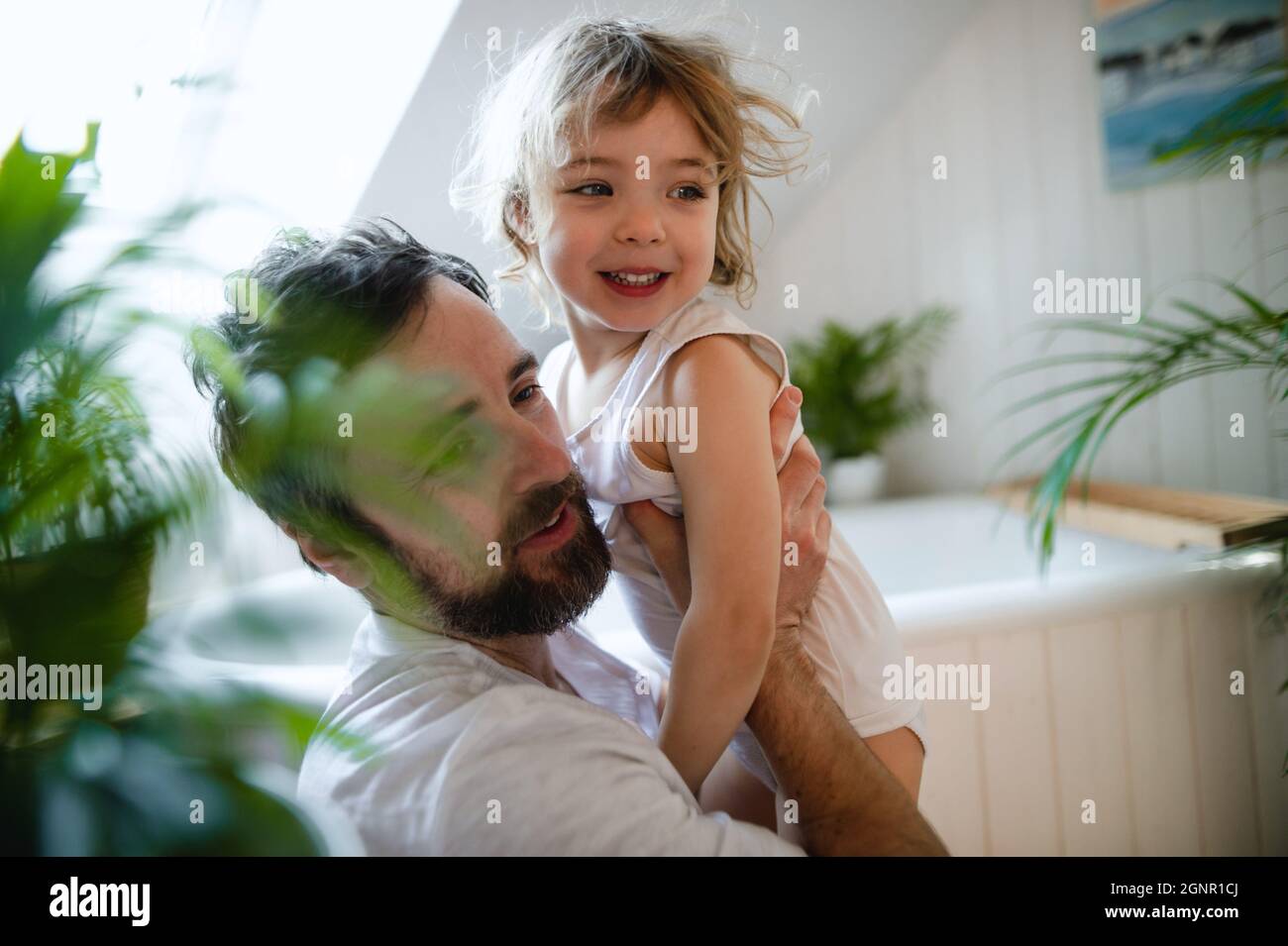 Mature father with small daughter indoors in bathroom at home. Stock Photo