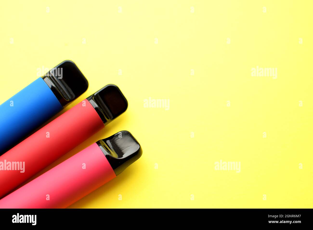 Three electronic cigarettes on a yellow background. Place for your text. Stock Photo