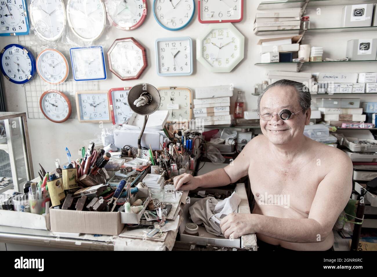 Phang Nga, Thailand - FEBRUARY 1, 2016: Portrait of an Asian elder watchmaker with eyeglass loupe working in his watch shop. Thai Mueang. Stock Photo