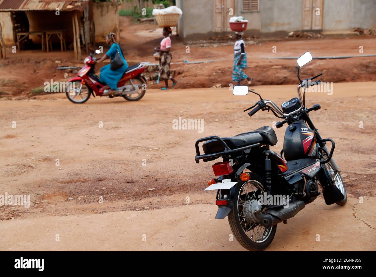 Street scene with african woman riding a motorcycle. Benin. Stock Photo