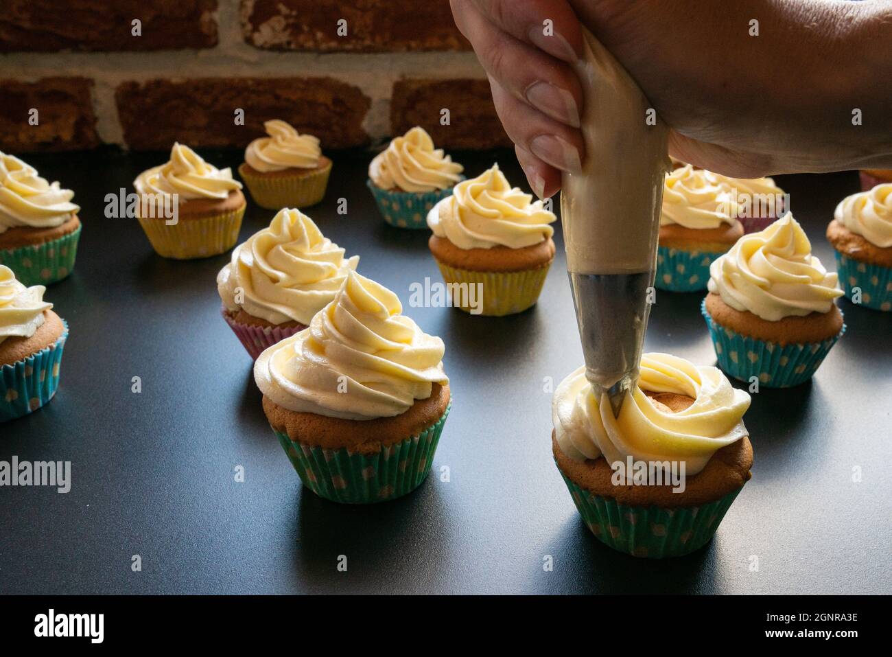 hand is showing how to decorate cupcakes with butter cream Stock Photo