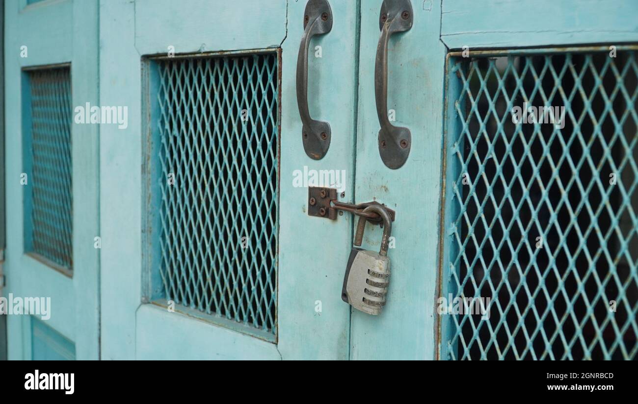 Vintage blue wooden folding door with metal rusted latch and unlocked padlock Stock Photo