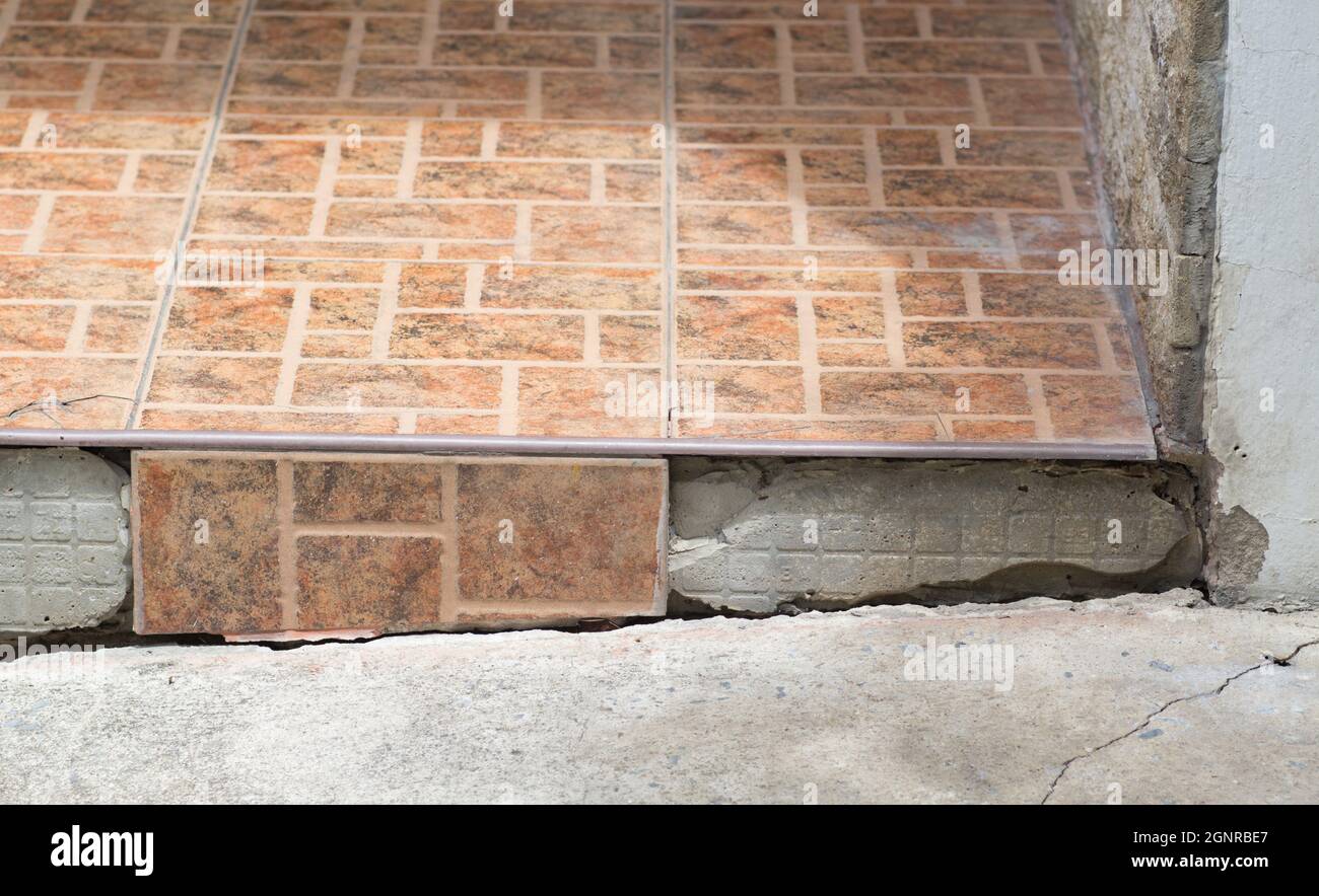 Cracked floor tiles, house damaged with floor subsidence. Stock Photo