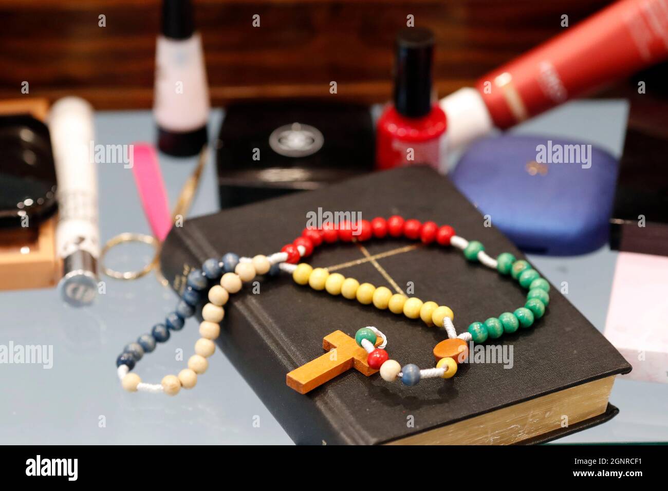 Makeup products, bible  and prayer beads on table. Stock Photo