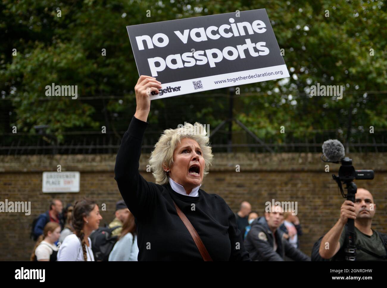 A protester with a No Vaccine Passports placard shouts to the passengers wearing face masks in a bus, during the demonstration. Stock Photo
