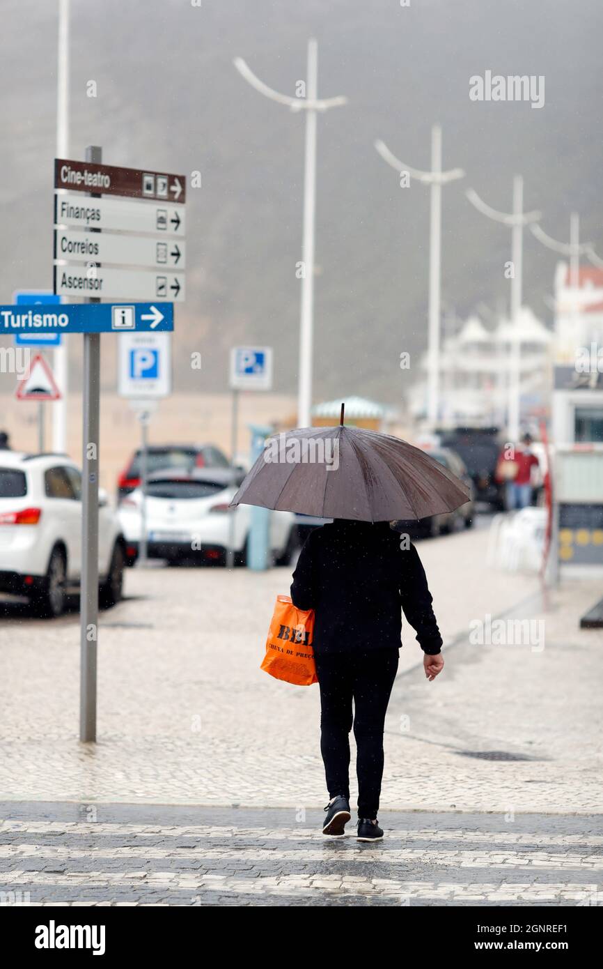 People walking with umbrella in rainy day scene.  Nazare. Portugal. Stock Photo