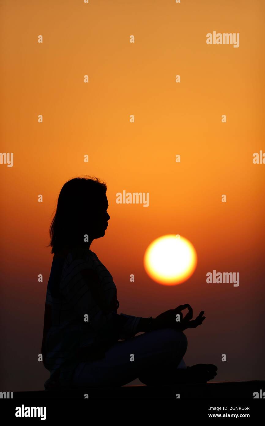 Woman practicing yoga pose and meditation at sunset.   Silence and relaxation concept. Stock Photo