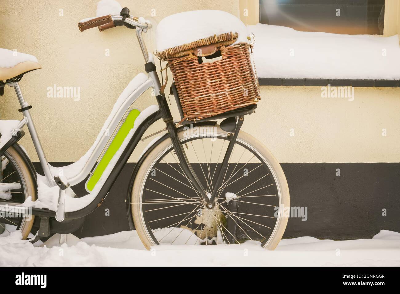 Dutch bicycle with basket covered with snow during wintertime parked  outside an old house Stock Photo - Alamy