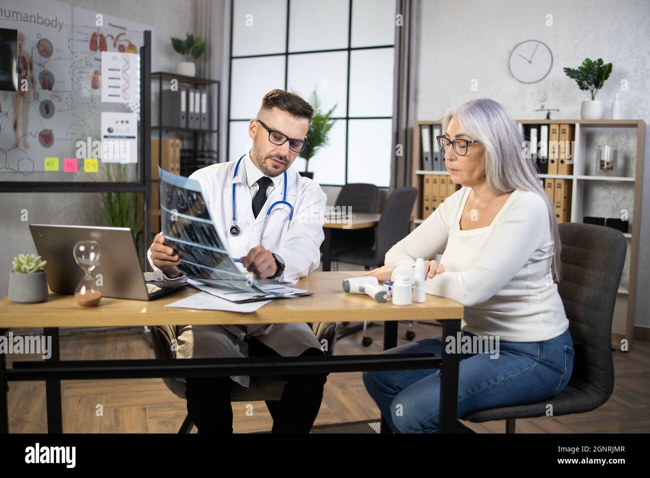 Qualified male doctor explaining results of x ray scan to caucasian