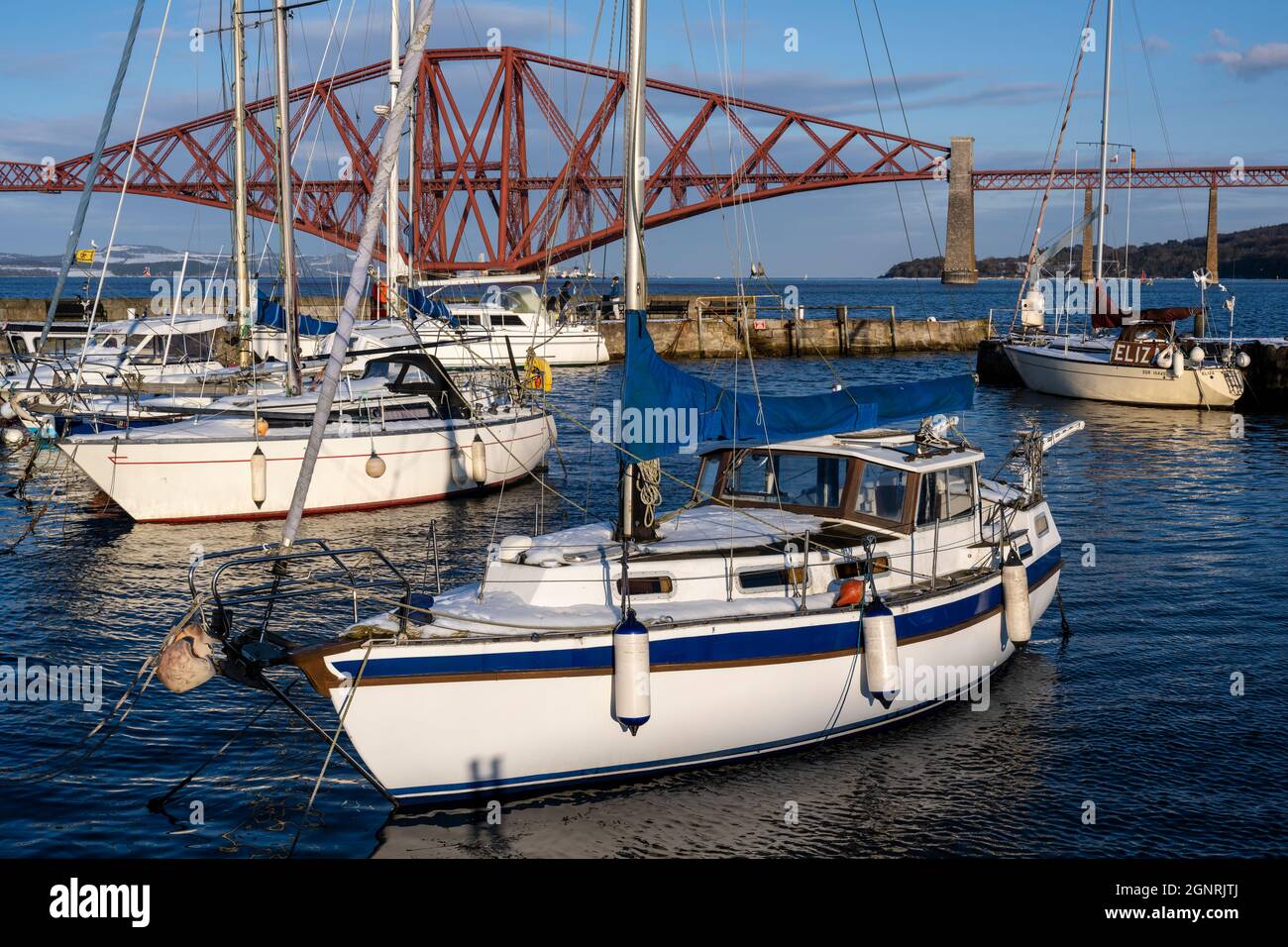 Yachts moored in South Queensferry harbour with backdrop of Forth Rail Bridge - South Queensferry, Scotland, UK Stock Photo
