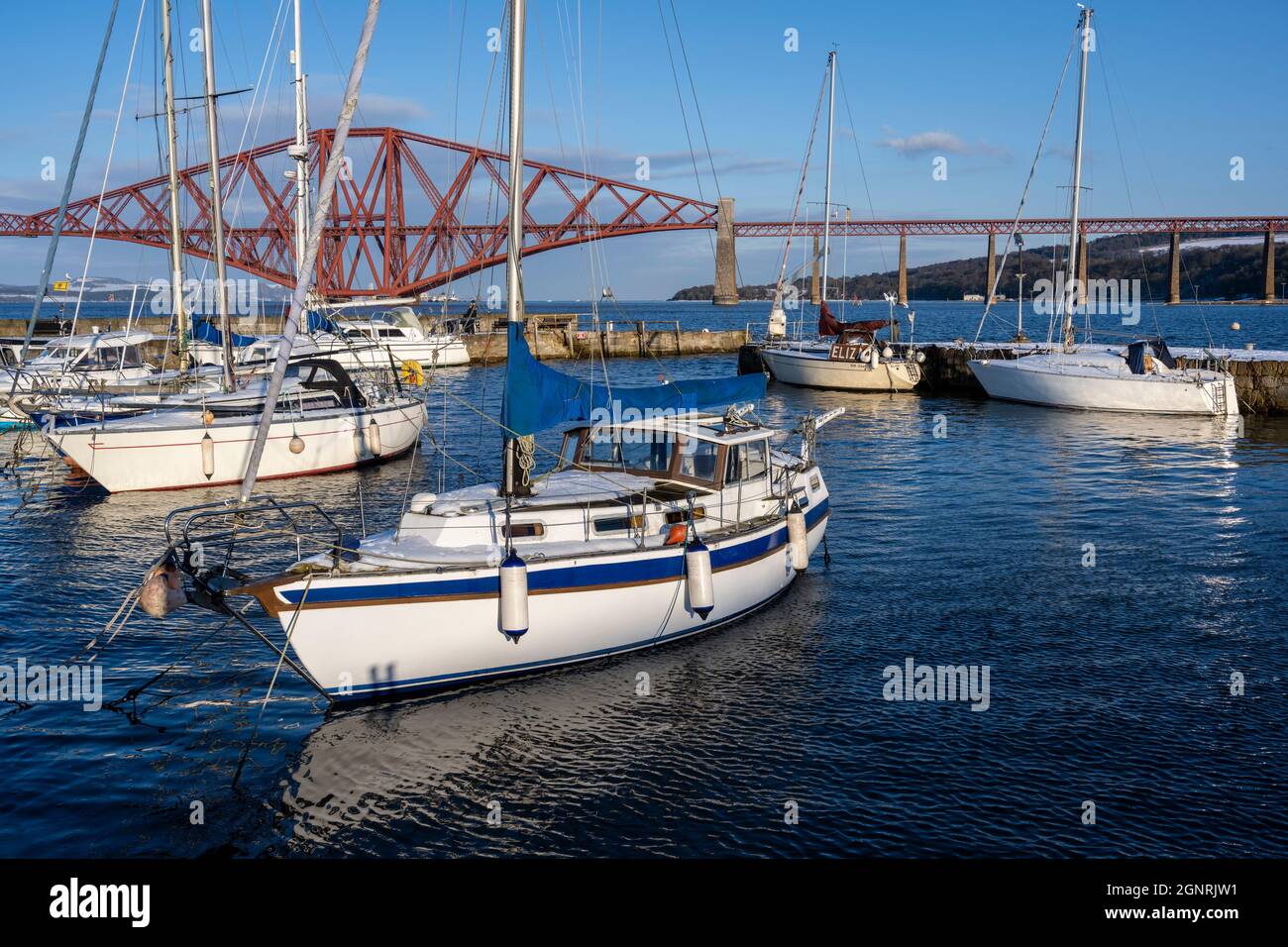 Yachts moored in South Queensferry harbour with backdrop of Forth Rail Bridge - South Queensferry, Scotland, UK Stock Photo