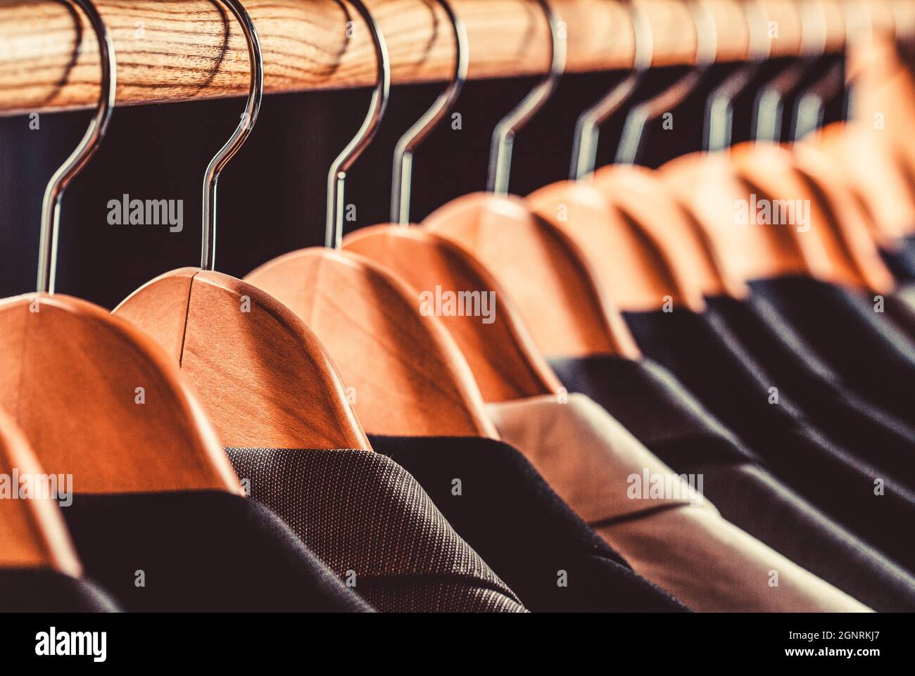 Mens suits in different colors hanging on hanger in a retail clothes