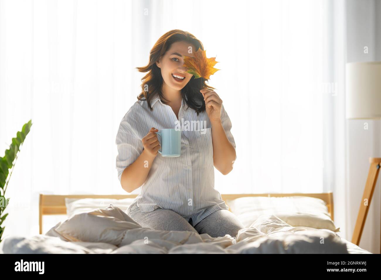 Happy young woman enjoying sunny morning on the bed Stock Photo - Alamy