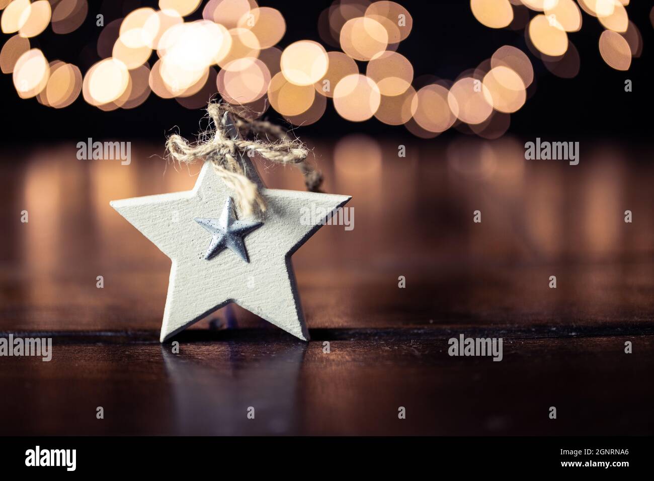 Christmas star on a wooden table with out of focus christmas lights in the background - bokeh, selective focus Stock Photo