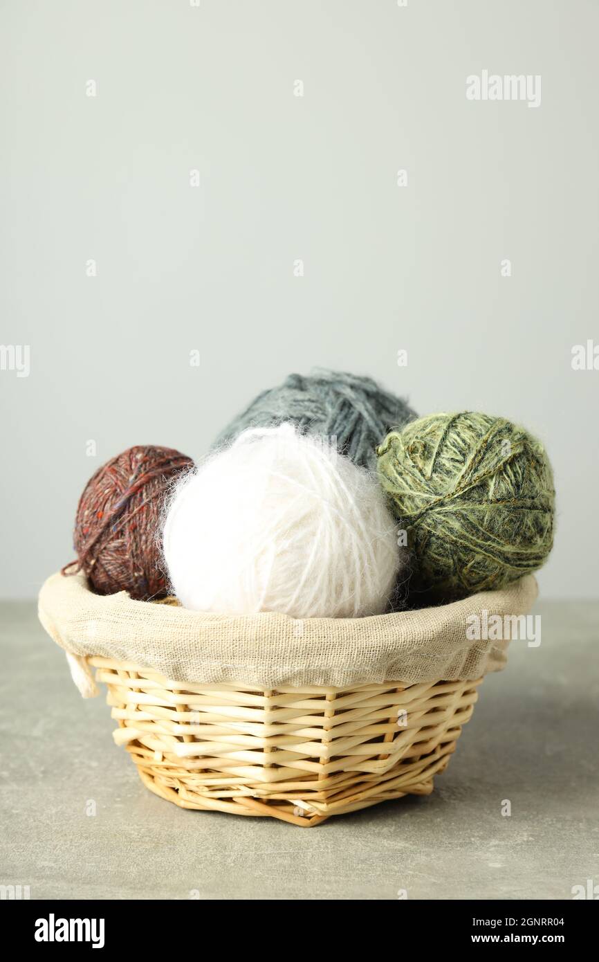 Wicker basket with yarn balls on light gray table Stock Photo