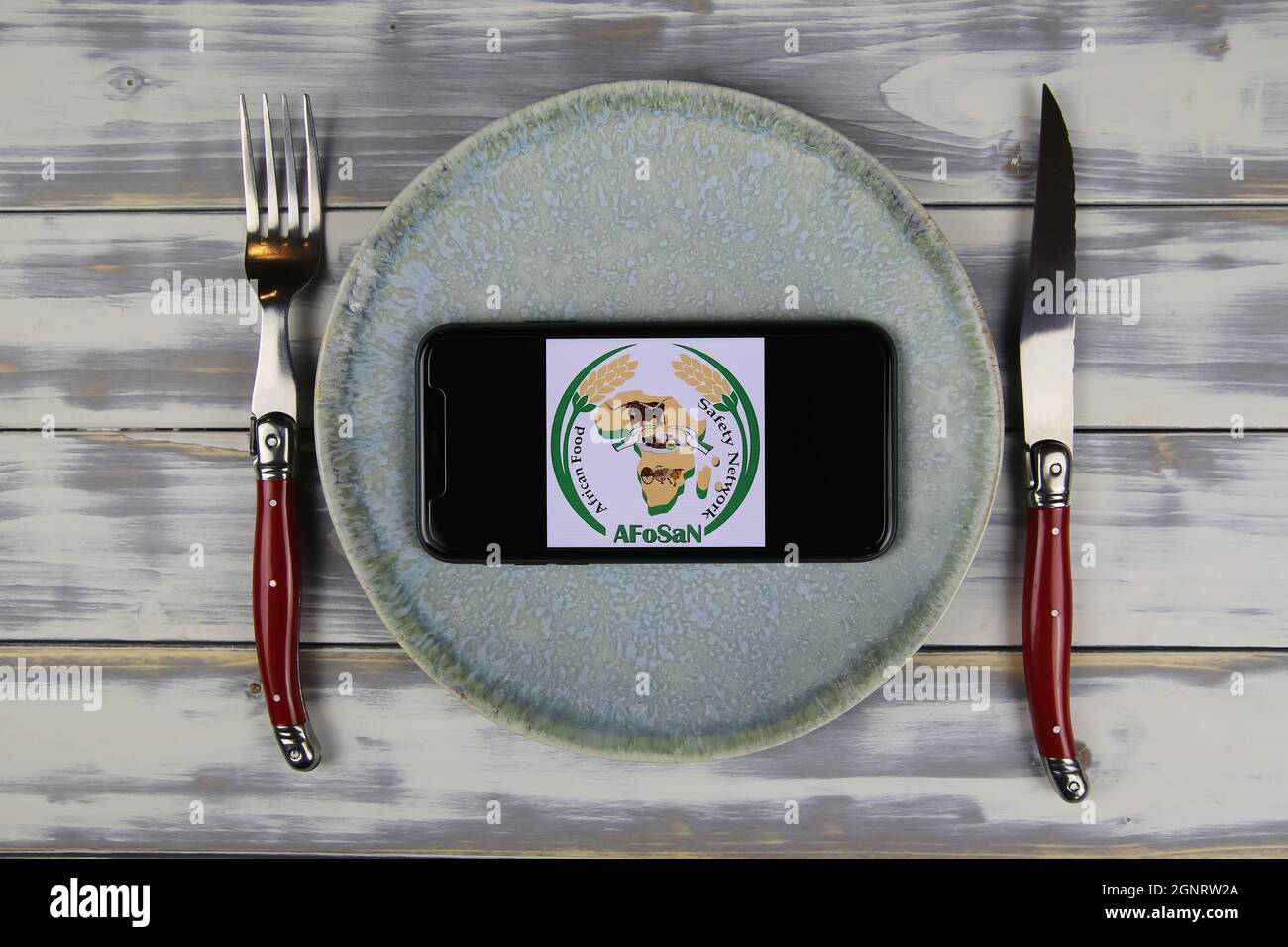 Viersen, Germany - June 9. 2021: Closeup of smartphone with logo lettering of african food safety network afosan on plate with cutlery (focus on cente Stock Photo