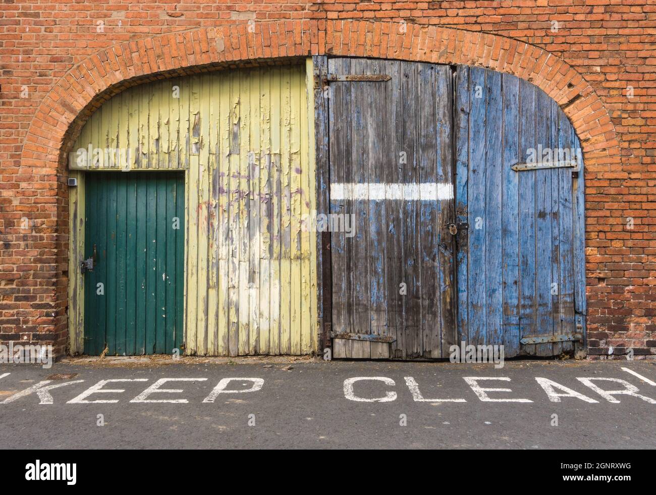 Keep Clear sign in front of wooden doors that have peeling paint and