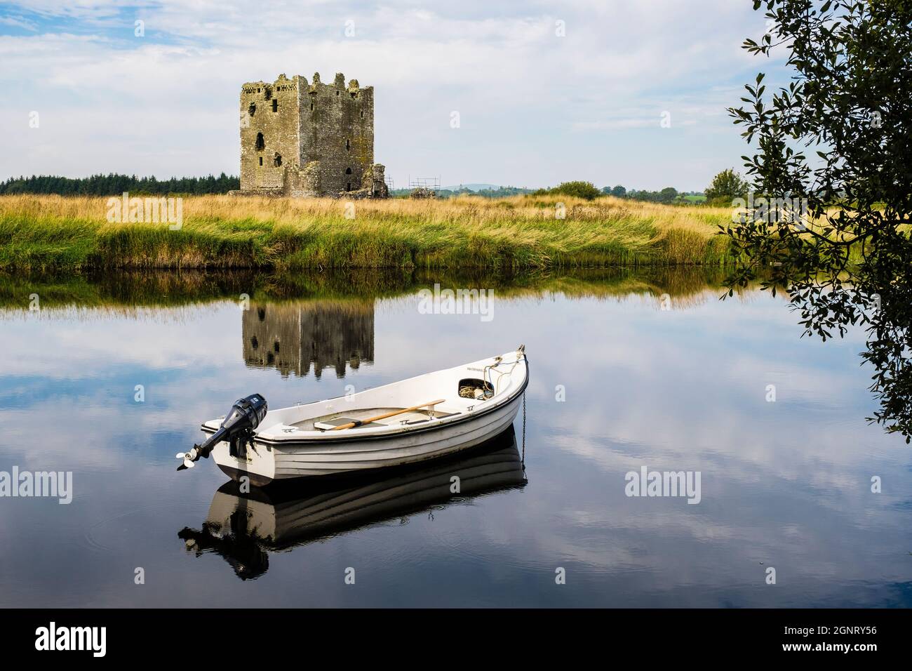 Threave Castle reflected in calm waters of the River Dee with small ferry boat. Threave, Castle Douglas, Dumfries and Galloway, Scotland, UK, Britain Stock Photo